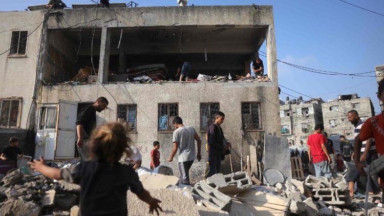 Abitanti di Jabalia, nel nord della Striscia, nei pressi di un edificio bombardato in un raid israeliano