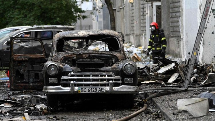 Um bombeiro ao lado de um carro incendiado após ataques em massa de drones e mísseis russos na cidade de Lviv, no oeste da Ucrânia, em 12 de julho de 2025, em meio à invasão russa da Ucrânia. (Foto de YURIY DYACHYSHYN / AFP)