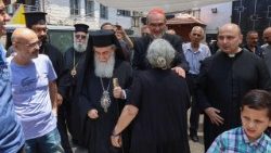 Il cardinale Pizzaballa (al centro) saluta un'anziana parrocchiana nel corso delle visita alla chiesa della Sacra Famiglia a Gaza. A sinistra, il patriarca greco ortodosso di Gerusalemme Teofilo III e a destra il parroco padre Gabriel Romanelli