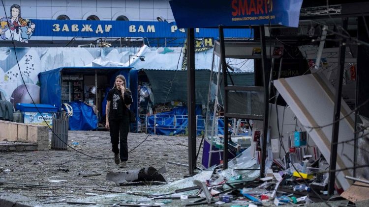 Uma garota com um celular caminha pelos destroços de um ataque russo em Kiev, em 21 de julho de 2025, em meio à invasão russa da Ucrânia. Ataques russos na capital da Ucrânia, Kiev, em 21 de julho, mataram pelo menos uma pessoa e incendiaram uma loja e uma escola, segundo autoridades municipais. Quatro distritos da cidade foram atacados, com relatos de prédios residenciais, um quiosque e um jardim de infância em chamas, informou o prefeito de Kiev, Vitali Klitschko, em outra publicação no Telegram. (Foto de OLEKSII FILIPPOV / AFP)