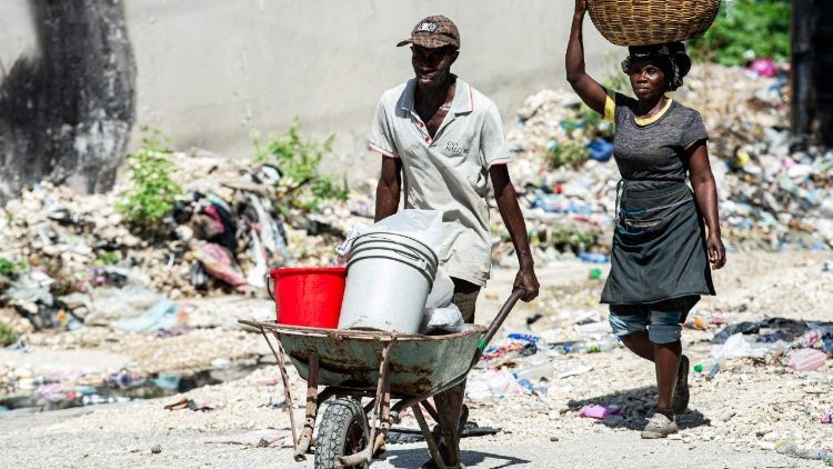 Haitianos carregam mercadorias pelo centro de Porto Príncipe em 21 de julho.