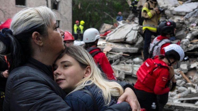 Moradores locais se consolam enquanto equipes de resgate ucranianas trabalham entre os escombros de um prédio residencial destruído após um ataque aéreo em Kiev em 31 de julho de 2025, em meio à invasão russa da Ucrânia. O presidente ucraniano, em 31 de julho de 2025, instou seus aliados a promoverem uma "mudança de regime" na Rússia, horas depois de um ataque russo com drones e mísseis em Kiev ter matado sete pessoas, incluindo um menino de seis anos. (Foto de OLEKSII FILIPPOV / AFP)