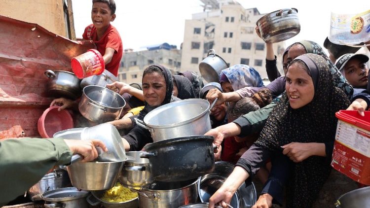 Palestinos recebem refeições em um centro de distribuição de alimentos na Cidade de Gaza, em 13 de agosto de 2025. O Exército israelense anunciou em 13 de agosto a aprovação do arcabouço para uma nova ofensiva na Faixa de Gaza,.