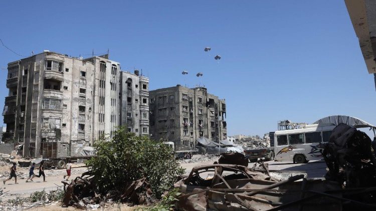Palestinian run towards aid pallets as they parachute down after being dropped from a military plane near Jabalia in the northern Gaza Strip on August 20