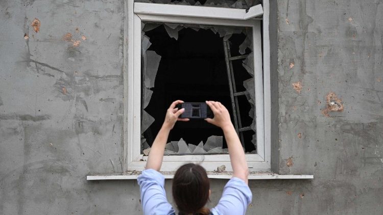 Uma mulher tira fotos com seu smartphone de uma janela quebrada de um prédio residencial danificado após ataques aéreos russos na cidade de Lviv, no oeste da Ucrânia, em 21 de agosto de 2025, em meio à invasão russa da Ucrânia. A Rússia lançou centenas de drones e mísseis contra a Ucrânia durante a noite, informou a Força Aérea Ucraniana em 21 de agosto de 2025, o maior ataque de Moscou em semanas, após os esforços liderados pelos EUA para deter a invasão do Kremlin. (Foto de YURIY DYACHYSHYN / AFP)