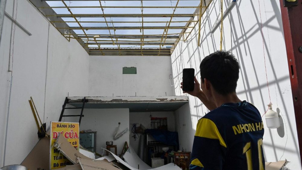 Um morador registra os danos em um telhado na vila de pescadores de Nhon Hai, perto de Quy Nhon, na província de Gia Lai, região central do Vietnã, em 7 de novembro de 2025, após a passagem do tufão Kalmaegi. O tufão Kalmaegi atingiu o Vietnã em 7 de novembro, causando mais cinco mortes após sua devastadora passagem pelas Filipinas, onde o número de mortos subiu para 188. (Foto de NHAC NGUYEN / AFP)