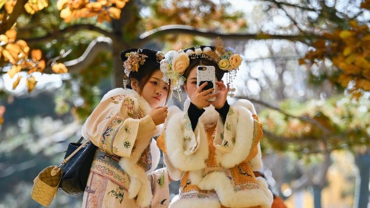 Due giovani in abiti tradizionali si scattano un selfie mentre camminano a Pechino