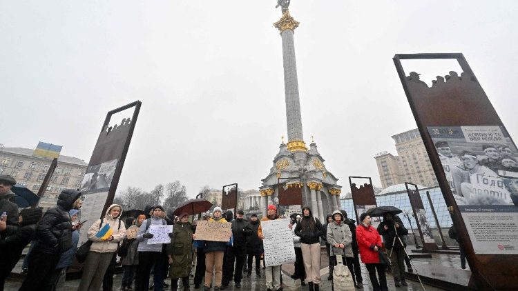 Manifestantes exibem cartazes durante um protesto anticorrupção na Praça da Independência, em Kiev, em 22 de novembro de 2025. (Foto de Sergei SUPINSKY / AFP)