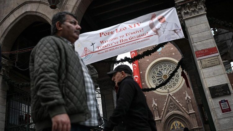 Pedestres passam em frente à Igreja de Santo Antônio de Pádua enquanto uma faixa de boas-vindas com um retrato do Papa Leão XIV é exibida em seu portão, antes de sua visita à Turquia, em Istambul, em 24 de novembro de 2025. (Foto de Ozan KOSE / AFP)