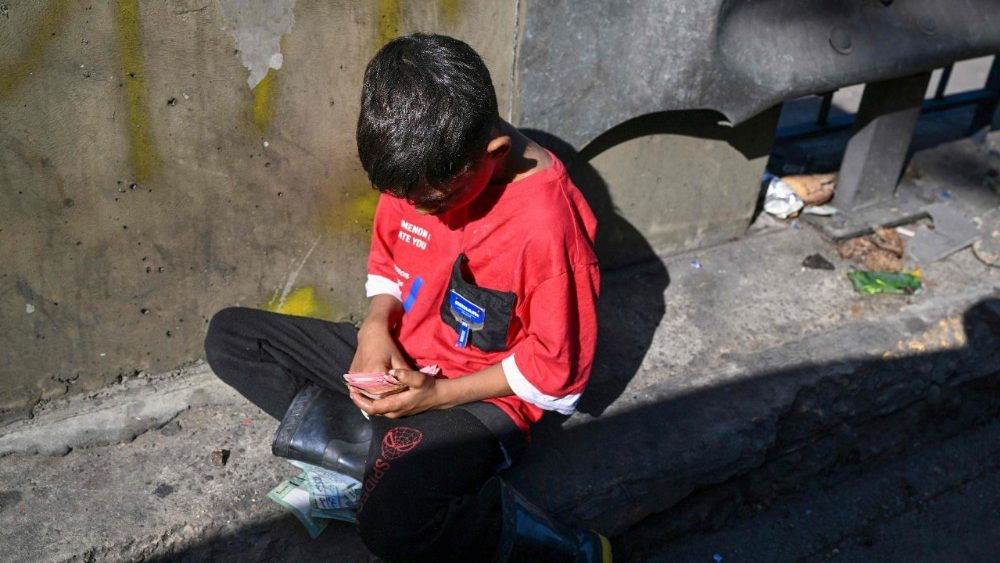 Um menino conta o dinheiro que recebeu de esmolas enquanto está sentado à beira de uma estrada em Beirute, em 26 de novembro de 2025. (Foto de Joseph EID / AFP)