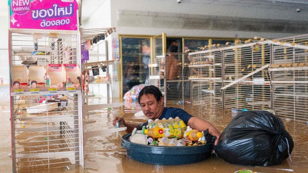 Um homem empurra um recipiente cheio de bebidas enquanto caminha pela água em uma loja de conveniência 7/11 inundada em Hat Yai, na província de Songkhla, no sul da Tailândia, em 26 de novembro de 2025, quando graves inundações afetaram milhares de pessoas no sul do país após dias de fortes chuvas. Dezenas de milhares de pessoas na Tailândia e na vizinha Malásia foram deslocadas pelas inundações generalizadas, com ruas submersas, casas alagadas e pelo menos 34 mortos, disseram autoridades em 26 de novembro. (Foto de Arnun Chonmahatrakool / THAI NEWS PIX / AFP)