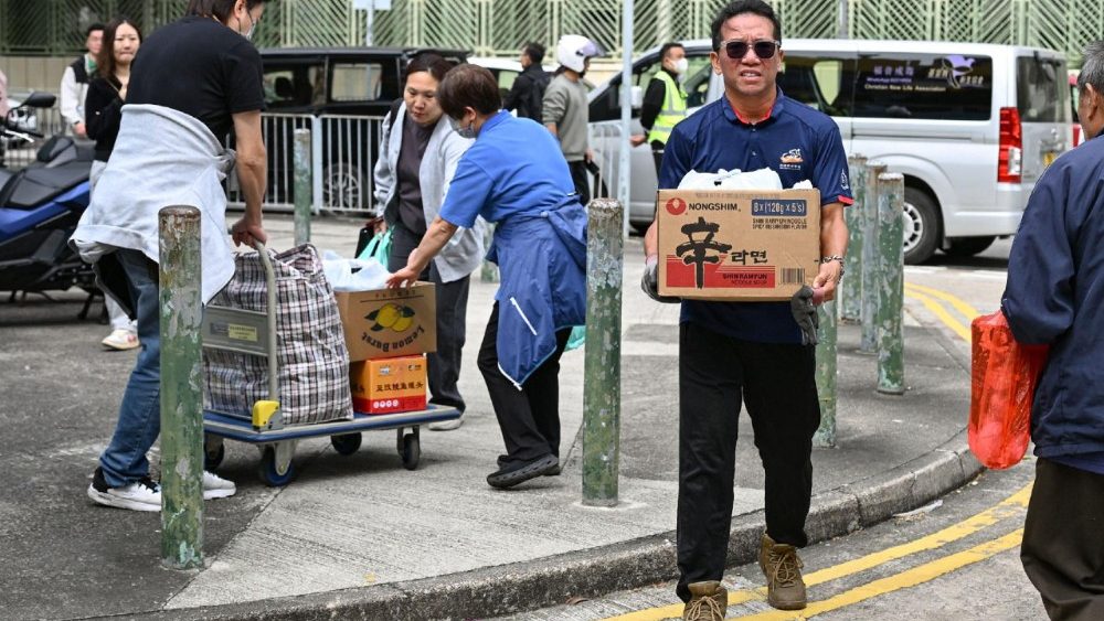 Moradores locais trazem itens essenciais para doação na Escola Secundária Fung Leung Kit, um dos centros comunitários designados para os moradores afetados após um grande incêndio que atingiu vários blocos de apartamentos no conjunto residencial Wang Fuk Court, no distrito de Tai Po, em Hong Kong, em 27 de novembro de 2025. Os bombeiros ainda combatiam o incêndio devastador em 27 de novembro, que destruiu um complexo de arranha-céus em Hong Kong, matando pelo menos 44 pessoas e deixando centenas de desaparecidos, segundo as autoridades. (Foto de Peter PARKS / AFP)
