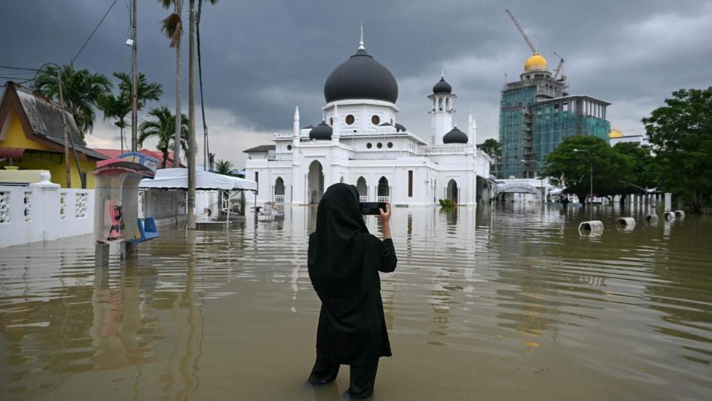 Uma mulher fotografa uma mesquita inundada em Kangar, no estado de Perlis, norte da Malásia, em 27 de novembro de 2025, enquanto graves inundações afetavam milhares de pessoas na região após dias de fortes chuvas. As inundações na Malásia, causadas por dias de chuvas intensas, atingiram oito estados, e os meteorologistas preveem mais chuvas nos próximos dias. Mais de 27.000 pessoas foram evacuadas para dezenas de abrigos temporários esta semana, e uma morte foi registrada em um dos estados mais afetados, Kelantan, na costa nordeste, segundo autoridades de resgate. (Foto de MOHD RASFAN / AFP)