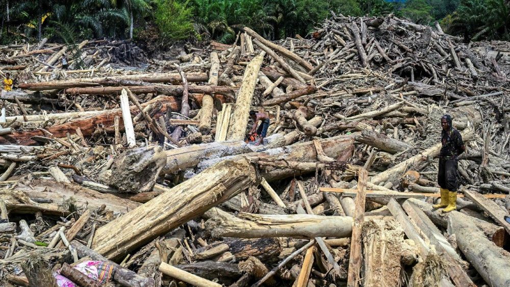 Moradores cortam toras de madeira arrastadas por uma enchente repentina, com a intenção de usá-las como material para reconstruir suas casas danificadas em Garoga, província de Sumatra do Norte, em 4 de dezembro de 2025. As previsões de chuva aumentaram os temores de mais danos na Indonésia e no Sri Lanka, países já atingidos por enchentes, após as inundações anteriores terem matado mais de 1.500 pessoas nesses quatro países. (Foto de YT HARIONO / AFP)