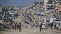 Palestinians walk in a street next to the rubble of destroyed buildings in the Jabalia refugee camp, in the northern Gaza Strip
