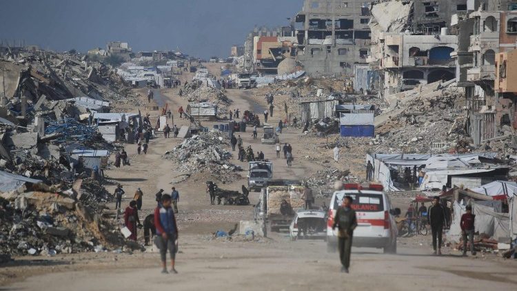 Palestinians walk in a street next to the rubble of destroyed buildings in the Jabalia refugee camp, in the northern Gaza Strip