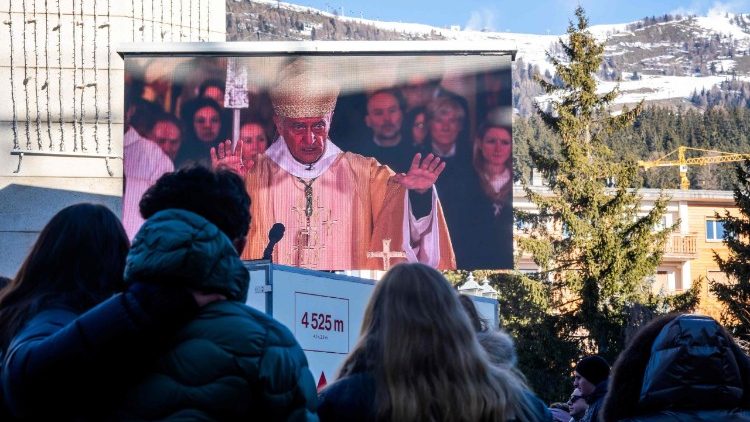 Pessoas em luto se re&uacute;nem em frente a um tel&atilde;o gigante para assistir a uma missa dominical dedicada &agrave;s v&iacute;timas do inc&ecirc;ndio no bar e lounge 'Le Constellation', na Capela Cat&oacute;lica de Saint-Christophe em Crans-Montana, em 4 de janeiro de 2026.