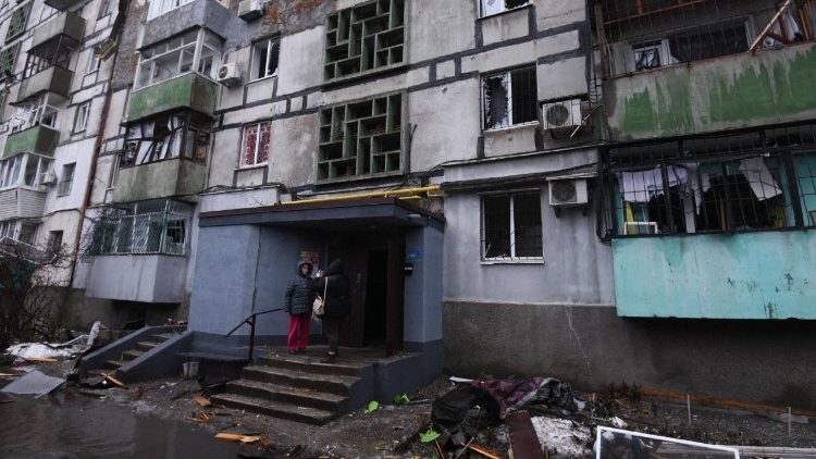 Moradores locais observam da varanda de um pr&eacute;dio residencial danificado ap&oacute;s um ataque de drone em Dnipro, em 7 de janeiro de 2026, em meio &agrave; invas&atilde;o russa na Ucr&acirc;nia. (Foto de Mykola Synelnykov / AFP)