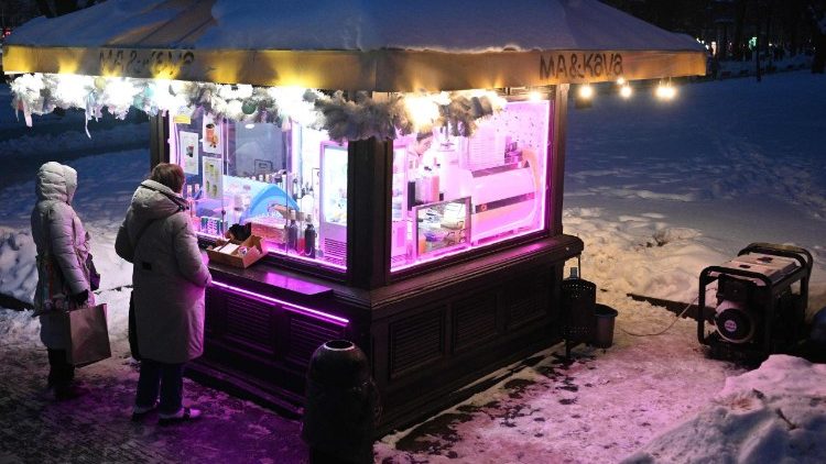 Clientes aguardam em uma barraca de caf&eacute; abastecida com energia el&eacute;trica gerada por um gerador durante um corte de energia programado no centro de Lviv, ap&oacute;s ataques russos com m&iacute;sseis e drones &agrave; infraestrutura energ&eacute;tica ucraniana em meio &agrave; invas&atilde;o russa da Ucr&acirc;nia, em 13 de janeiro de 2026. (Foto de YURIY DYACHYSHYN / AFP)