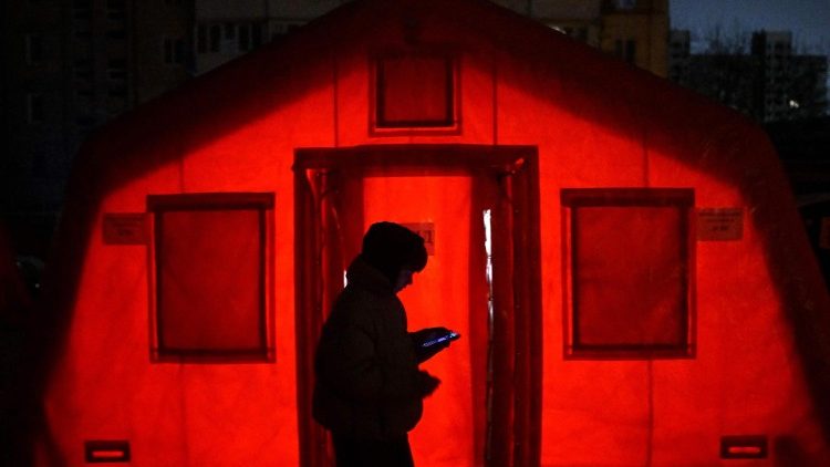 Um morador passa por uma tenda com aquecimento montada no p&aacute;tio de um pr&eacute;dio residencial em Kiev, em 15 de janeiro de 2026, em meio &agrave; invas&atilde;o russa da Ucr&acirc;nia. (Foto de Sergei Gapon / AFP)