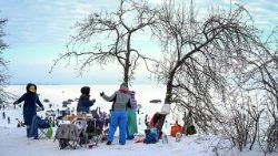 वर्फ के बीच लोग घर से बाहर खाना खाते हुए