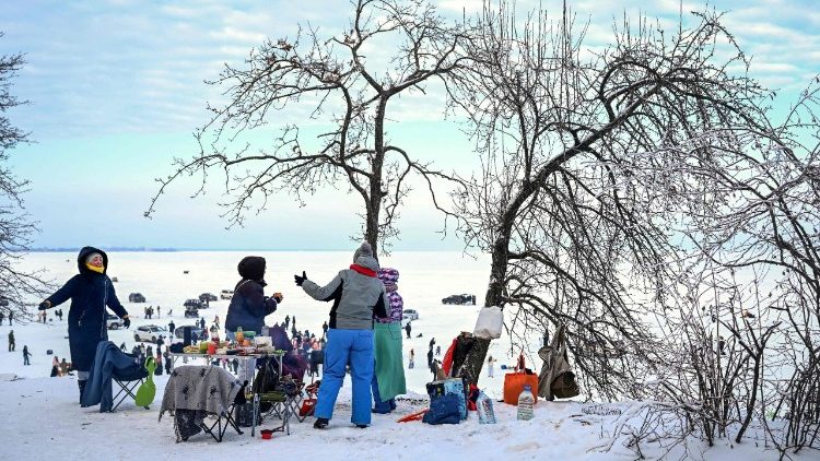 वर्फ के बीच लोग घर से बाहर खाना खाते हुए