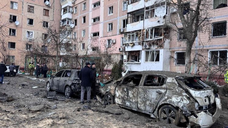 Pessoas observam carros queimados e um pr&eacute;dio residencial danificado em uma &aacute;rea atingida por um ataque a&eacute;reo em um bairro residencial de Zaporizhzhia, em 28 de janeiro de 2026, durante a invas&atilde;o russa da Ucr&acirc;nia. (Foto de Darya Nazarova / AFP)