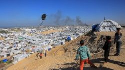 Bambini fanno volare un aquilone in un campo per sfollati a Gath nella Striscia di Gaza (Bashar Taleb/Afp)