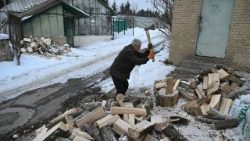 Um idoso ucraniano racha lenha na neve