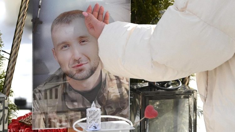 Iryna, vi&uacute;va de Yuriy, um soldado ucraniano morto em combate, toca em seu retrato enquanto visita seu t&uacute;mulo no Dia dos Namorados, no Cemit&eacute;rio Militar de Lychakiv, em Lviv, em 14 de fevereiro de 2026, em meio &agrave; invas&atilde;o russa da Ucr&acirc;nia. (Foto de YURIY DYACHYSHYN / AFP)