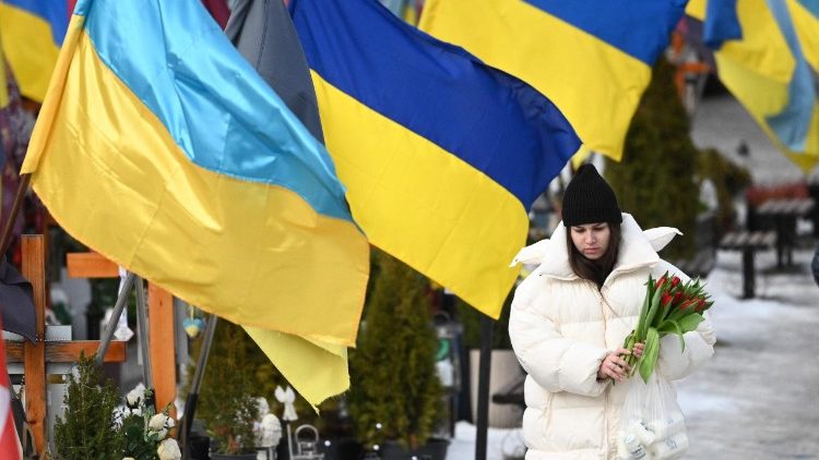 Uma pessoa em luto segura flores no Cemit&eacute;rio Militar de Lychakiv, em Lviv, no Dia dos Namorados, em 14 de fevereiro de 2026, em meio &agrave; invas&atilde;o russa da Ucr&acirc;nia. (Foto de YURIY DYACHYSHYN / AFP)