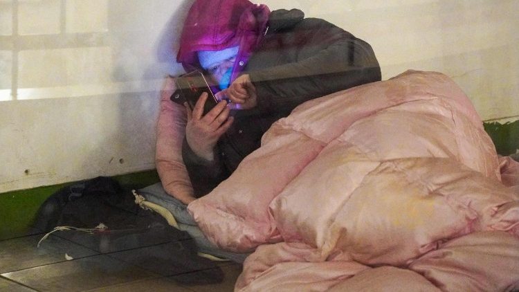 Uma mulher olha para o celular enquanto se abriga em uma esta&ccedil;&atilde;o de metr&ocirc; durante um alerta de ataque a&eacute;reo, em Kiev, na madrugada de 17 de fevereiro de 2026, em meio &agrave; invas&atilde;o russa da Ucr&acirc;nia. (Foto de Serhii Okunev / AFP)