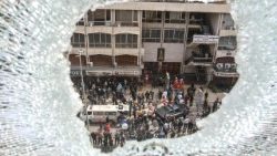 A shattered window overlooks first aid responders and security forces in Southern Lebanon  (Photo by MAHMOUD ZAYYAT / AFP)