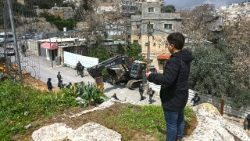 A boy looks at Israeli security forces patrolling as Jerusalem municipality workers prepare to demolish a house belonging to a Palestinian family