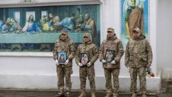 Soldati ucraini tengono in mano i ritratti delle tre vittime uccise giorni prima in un attacco di droni russi contro un edificio residenziale a Odessa