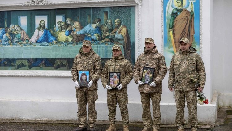 Soldati ucraini tengono in mano i ritratti delle tre vittime uccise giorni prima in un attacco di droni russi contro un edificio residenziale a Odessa