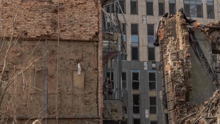 A woman stands in an apartment's balcony at the site of heavily damaged buildings following a Russian air attack in Dnipro, on April 16, 2026, amid the Russian invasion of Ukraine. Massive Russian strikes on Ukraine left at least 19 people dead overnight from April 15 to April 16, particularly in Kyiv and Odesa, Ukrainian authorities said on April 16, 2026, describing these attacks as among the deadliest in recent weeks. (Photo by Roman PILIPEY / AFP)