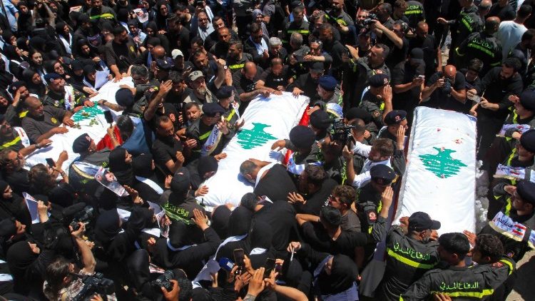 Mourners gather round the coffins of three Lebanese Civil Defence members killed in an Israeli strike
