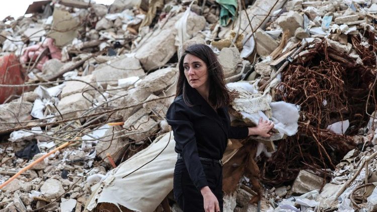 A woman stands on the rubble of her house in Beirut after an Israeli strike that killed her parents