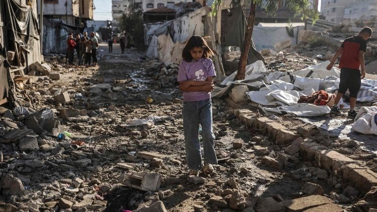 Una bambina palestinese cammina tra le macerie di Gaza City