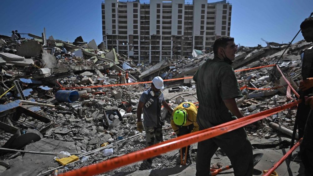 Equipes de resgate e voluntários procuram por pessoas desaparecidas em meio aos escombros da praia de Los Cocos, em Caraballeda, estado de La Guaira, Venezuela, em 1º de julho de 2026, após os terremotos gêmeos de 24 de junho. Venezuelanos, com ajuda de todo o mundo, ainda buscavam sobreviventes em 1º de julho de 2026, uma semana após os terremotos devastadores que mataram quase 2.000 pessoas e deixaram milhares desaparecidas. (Foto de Juan Barreto / AFP)
