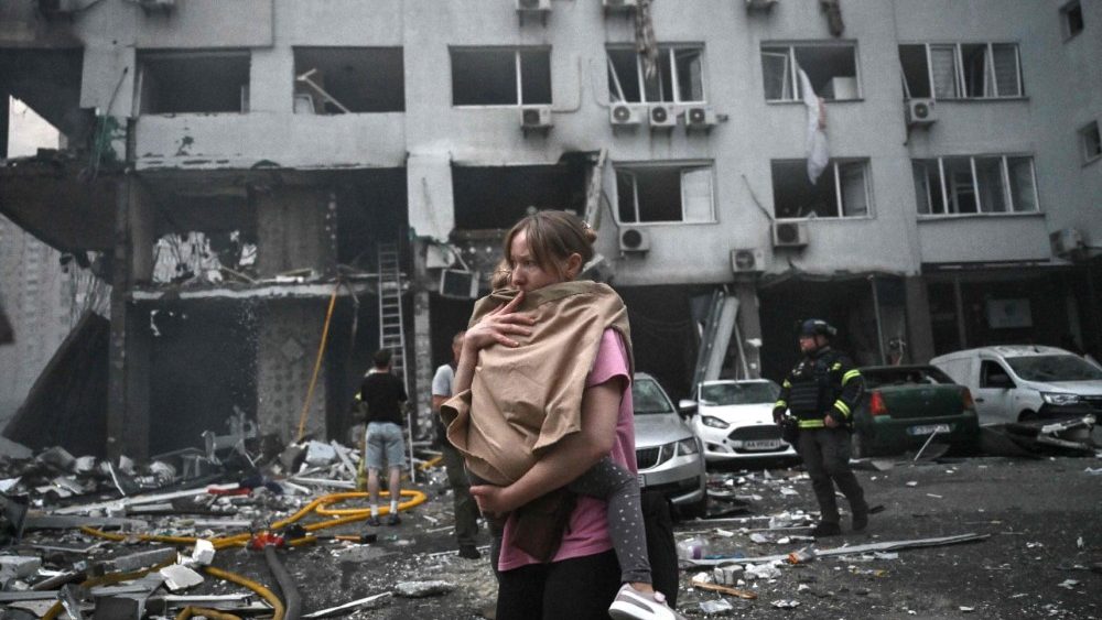 Uma mulher, moradora de um prédio residencial danificado, segura sua filha após um ataque de mísseis russos à capital ucraniana, Kiev, em 6 de julho de 2026, em meio à invasão russa na Ucrânia. A Rússia atacou a região de Kiev, na Ucrânia, com mísseis balísticos em 6 de julho, na véspera de uma cúpula da OTAN na Turquia. (Foto de Genya Savilov / AFP)