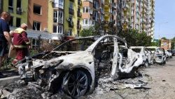 Personas caminan junto a vehículos dañados estacionados en una calle tras los ataques con misiles en Kyiv, el 19 de julio de 2026, en el contexto de la invasión rusa de Ucrania.