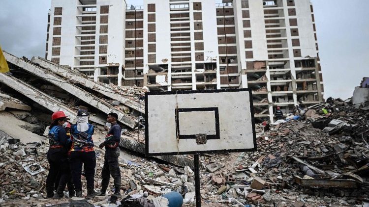 Volontari parlano tra le macerie di un edificio dell'Obras del Poder Popular (OPP) a Caraballeda, in Venezuela (Juan Barreto/Afp)