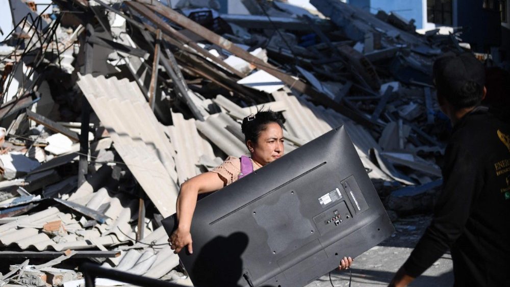 Uma mulher carrega uma televisão em meio aos escombros de um prédio que desabou após um terremoto em Pereira, Colômbia, em 10 de agosto de 2026. Um forte terremoto atingiu a Colômbia e países vizinhos da América Latina em 10 de agosto de 2026, com equipes médicas correndo para ajudar as vítimas após prédios serem danificados ou desabarem em diversas cidades. O Serviço Geológico da Colômbia e seu equivalente americano, o USGS, registraram magnitude 7,4, com epicentro a 100 km de profundidade no oeste do país. Inicialmente, a Colômbia havia estimado a magnitude em 6,6. (Foto de Jaime Saldarriaga / AFP)
