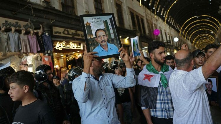 Un cittadino siriano porta con s&eacute; la foto di un parente ucciso durante la guerra civile, al termine del processo contro l'ex presidente Assad, a Damasco, l'11 agosto