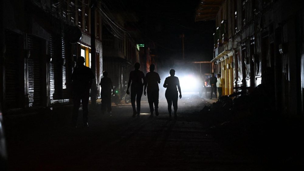 Sobreviventes caminham por uma rua durante um apagão após um terremoto em El Cairo, Valle del Cauca, Colômbia, em 11 de agosto de 2026. Equipes de resgate, soldados e voluntários vasculharam os escombros de prédios residenciais e comerciais em toda a região oeste da Colômbia, numa corrida contra o tempo para encontrar sobreviventes. (Foto de Raul Arboleda / AFP)