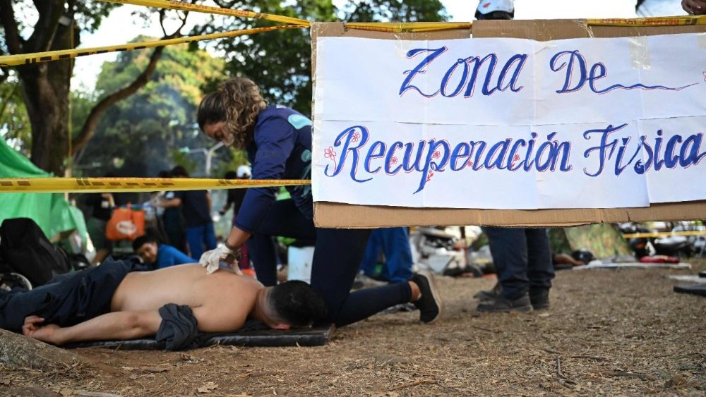 Um socorrista recebe uma massagem em uma área de recuperação improvisada perto de prédios desabados após um terremoto em Cali, Colômbia, em 14 de agosto de 2026. As chances de encontrar sobreviventes do terremoto na Colômbia diminuíram significativamente em 14 de agosto, quatro dias após o tremor de magnitude 7,4, embora os esforços de resgate continuassem, já que centenas de pessoas permaneciam desaparecidas. (Foto de Raul Arboleda / AFP)