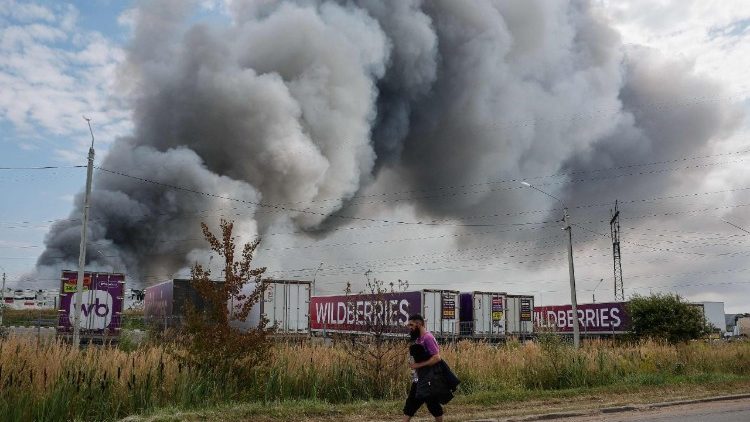 Un dipendente di Wildberries passa accanto a una colonna di fumo che si alza durante un incendio nel complesso logistico dell'azienda russa di e-commerce Wildberries, vicino alla città di Podolsk, alle porte di Mosca