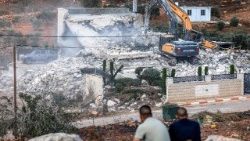 Palestinesi osservano i bulldozer israeliani mentre demoliscono un edificio, adducendo come motivazione la mancanza di un permesso di costruzione, a Qalandia, a sud di Ramallah